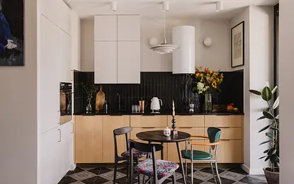 Kuchnia z białymi meblami, czarnym blatem i kolorowymi kwiatami, współczesny styl