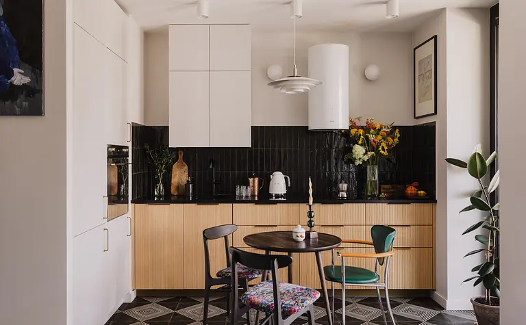 Kuchnia z białymi meblami, czarnym blatem i kolorowymi kwiatami, współczesny styl