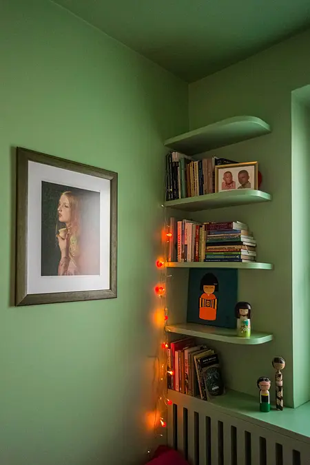 Wnętrze z zieloną ścianą, półkami na książki, vintage i dopamine decor.