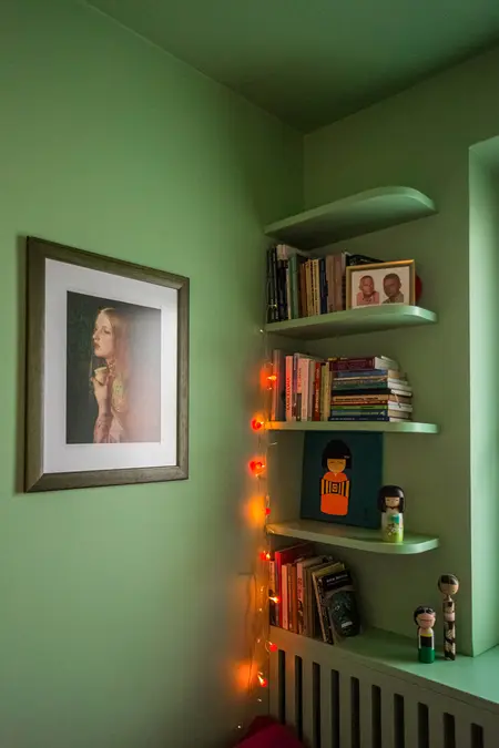 Wnętrze z zieloną ścianą, półkami na książki, vintage i dopamine decor.