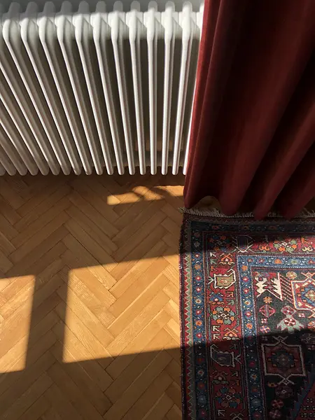 Wnętrze z eklektycznym dywanem, skandynawskim grzejnikiem i vintage zasłonami.