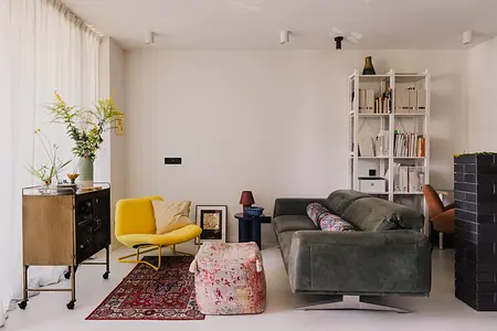 Wnętrze współczesnego salonu z zieloną sofą, żółtym fotelem i dekoracjami.