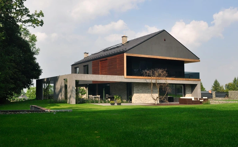 Widok nowoczesnego domu z dużymi oknami i ogrodem, styl minimalistyczny i minimaluxe.