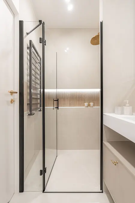 Współczesna łazienka z prysznicem, jasnymi kaflami i nowoczesnymi akcesoriami.