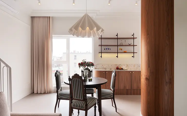 Wnętrze jadalni w stylu eklektycznym i vintage z drewnianym stołem i roślinami.