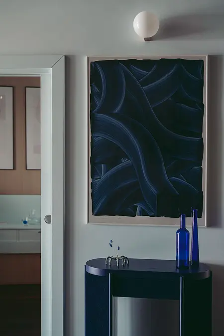 Eklektyczna przestrzeń z niebieskim obrazem, minimalistycznymi meblami i skandynawskim stylem.
