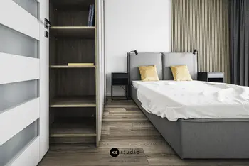 Sypialnia w stylu japandi z szarym łóżkiem i minimalistycznym wystrojem.