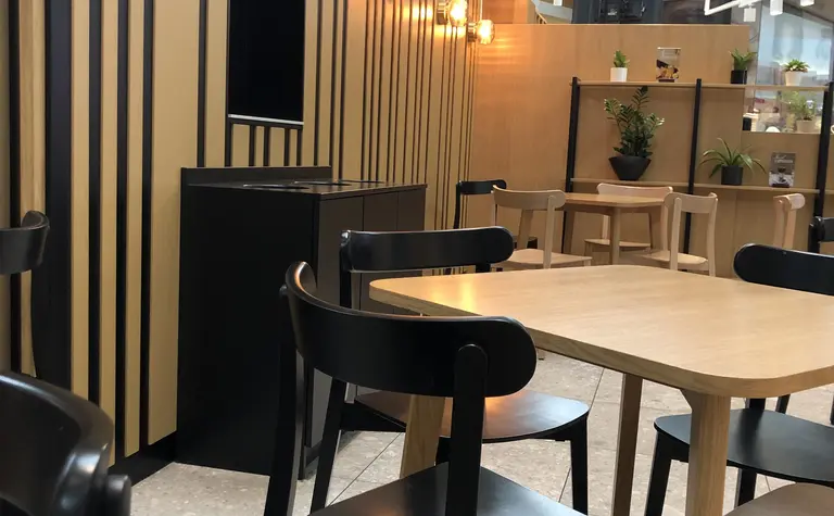 Wnętrze kawiarni w stylu japandi, minimalistycznym i nowoczesnym z drewnianymi detalami.