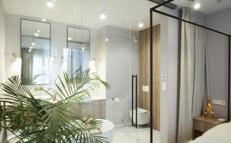Wnętrze łazienki z białą wanną i drewnianymi detalami, styl quiet luxury.