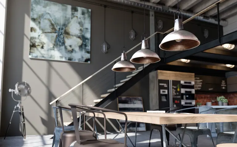 Wnętrze jadalni z drewnianym stołem, metalowymi lampami, industrialnymi detalami.