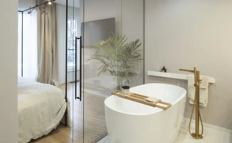 Nowoczesna łazienka z wolnostojącą wanną, drewnianymi detalami i roślinnością w stylu quiet luxury.
