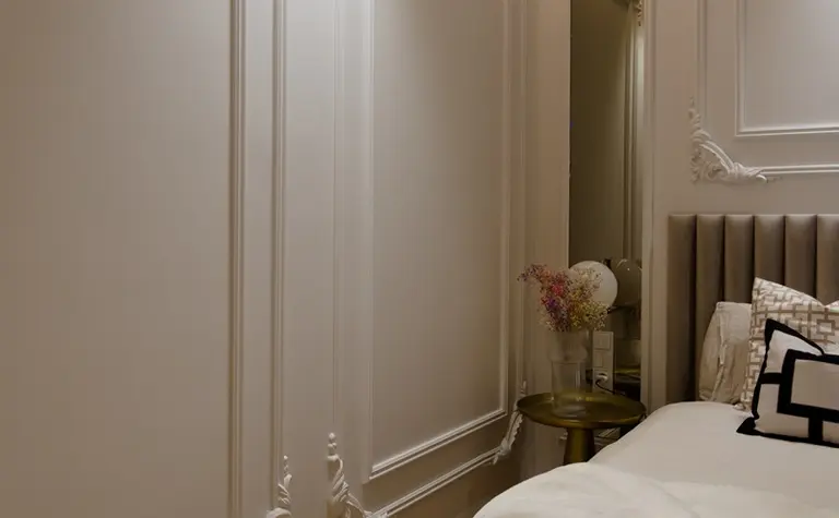 Wnętrze sypialni z jasnymi ścianami, drewnianą podłogą i eleganckimi detalami.