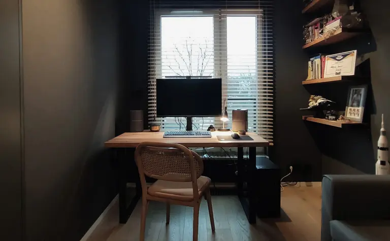Wnętrze gabinetu z biurkiem, komputerem i minimalistycznymi akcentami w stylu quiet luxury.