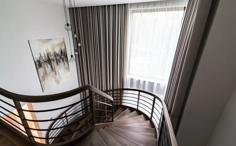 Klatka schodowa w stylu nowoczesnym z drewnianą balustradą, zasłonami i obrazem.