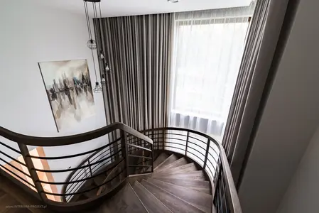 Klatka schodowa w stylu nowoczesnym z drewnianą balustradą, zasłonami i obrazem.