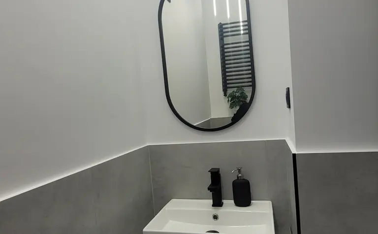 Nowoczesna łazienka z białą umywalką i szarymi płytkami w stylu minimalistycznym.
