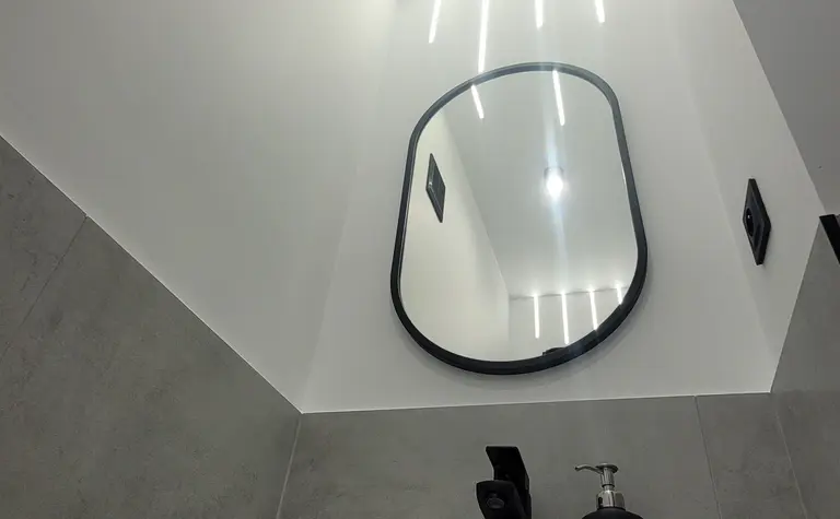 Minimalistyczna łazienka z białą umywalką i szarymi akcentami.