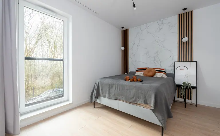 Wnętrze sypialni z szarym łóżkiem, marmurową ścianą, styl minimaluxe, nowoczesny i soft minimalizm.