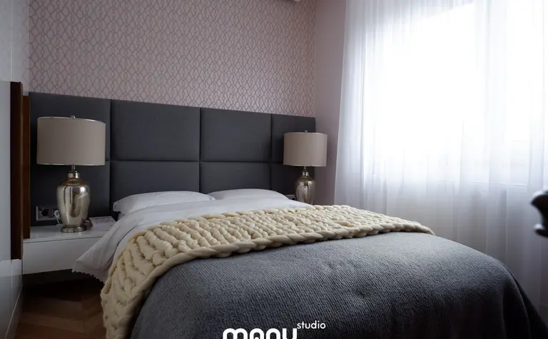 Sypialnia z szarym zagłówkiem, białą pościelą i lampą w tradycyjnym stylu.