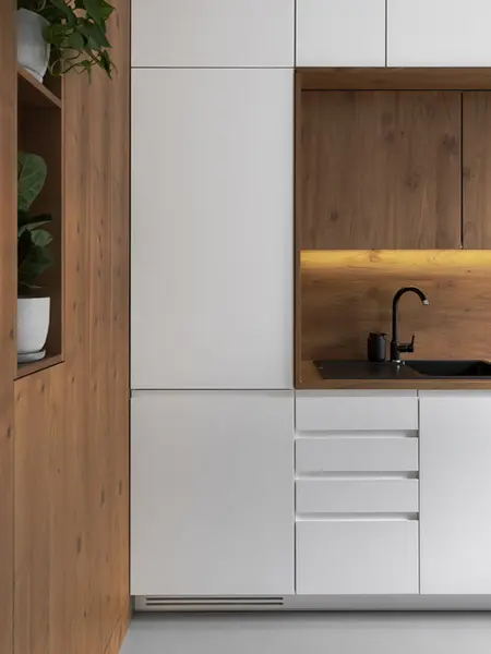 Nowoczesna kuchnia z białymi szafkami i drewnianym wykończeniem, minimalistyczny design.