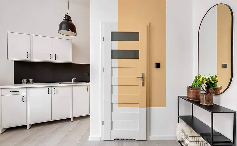 Wnętrze kuchni z białymi szafkami i czarnym blatem, industrialny styl