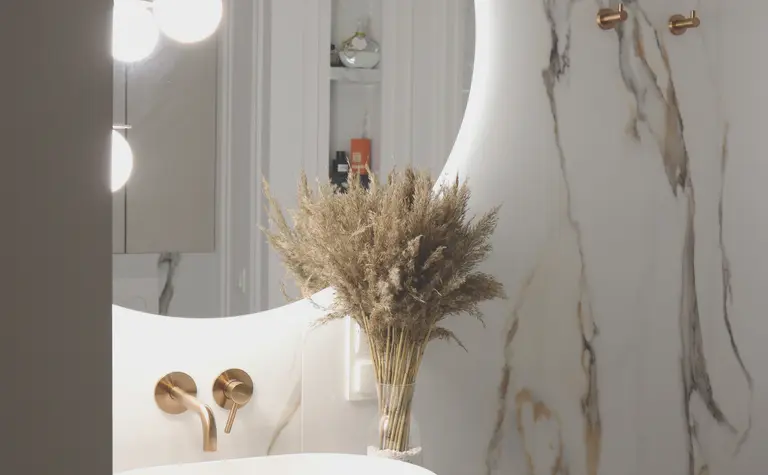 Nowoczesna łazienka z okrągłym lustrem, minimalistycznym designem i akcentami boho.