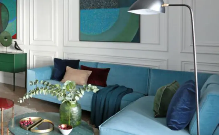 Wnętrze salonu w stylu minimaluxe i quiet luxury z niebieską sofą i zielonymi dodatkami.