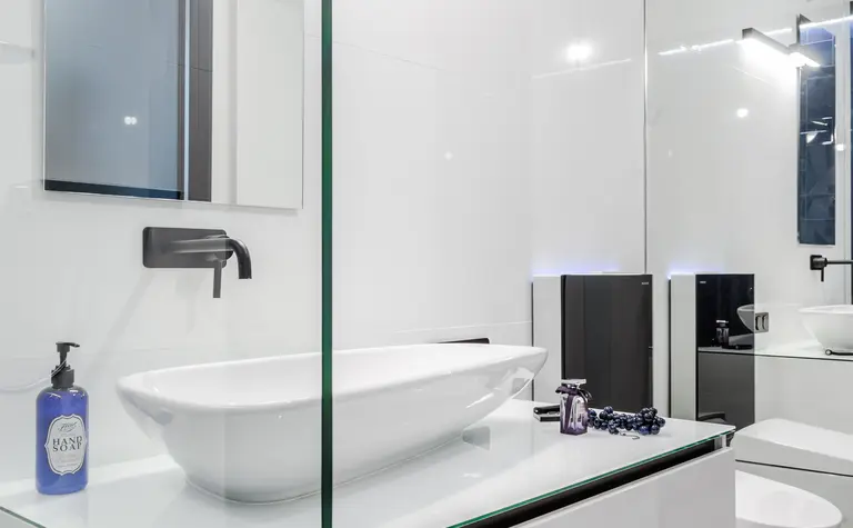 Nowoczesna łazienka z białą umywalką i czarnymi detalami, minimalistyczny design.