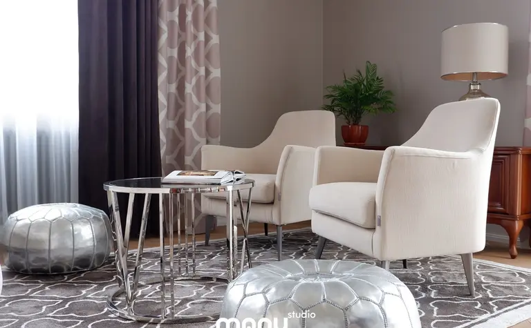 Wnętrze salonu z beżowymi fotelami, szklanym stolikiem i rośliną, styl tradycyjny.