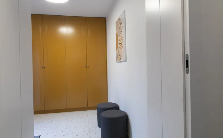 Przedpokój z szafą, szarymi siedziskami i nowoczesnym oświetleniem