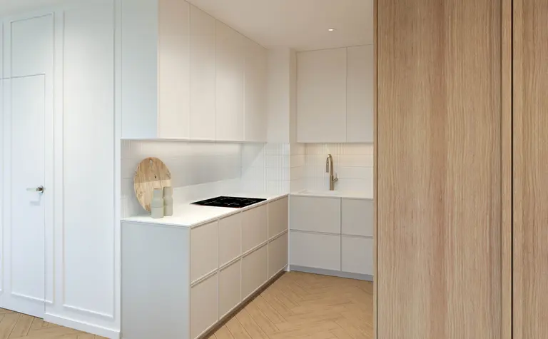 Kuchnia w stylu japandi i minimalistycznym z białymi meblami i drewnianymi detalami.