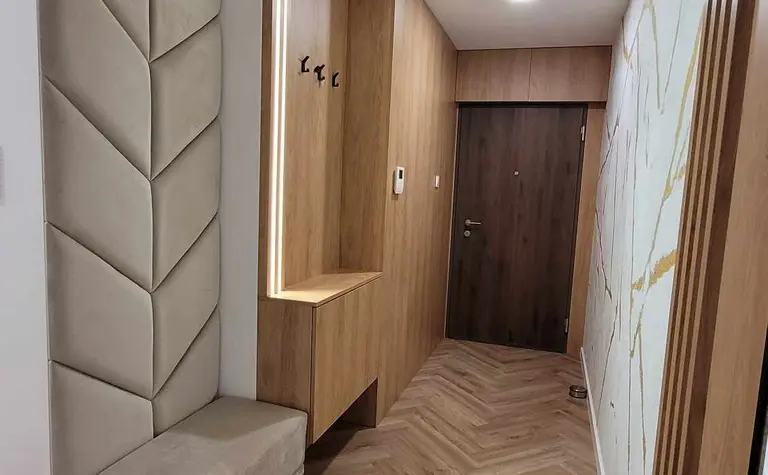 Przedpokój z nowoczesnym designem, drewnianą podłogą i eleganckimi detalami.