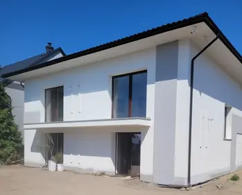 Nowoczesny budynek z dużymi oknami i białą elewacją w minimalistycznym stylu.