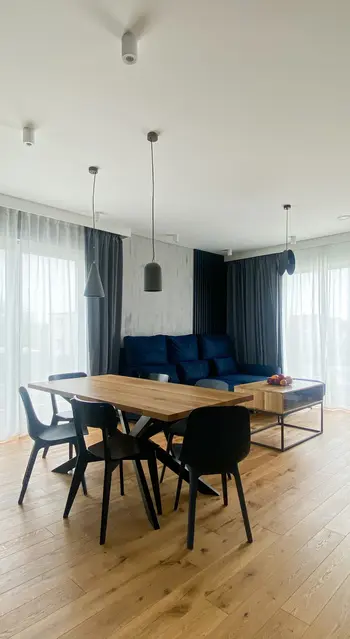 Wnętrze jadalni z drewnianym stołem, czarnymi krzesłami i niebieską sofą, minimalistyczne, nowoczesne, quiet luxury, skandynawskie, współczesne