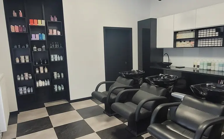 Wnętrze salonu fryzjerskiego z czarnymi fotelami i białymi meblami, styl industrialny i nowoczesny.