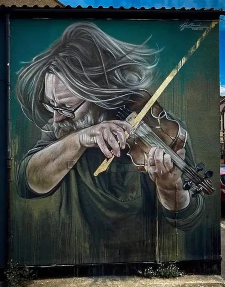 Mural artystyczny przedstawiający mężczyznę grającego na skrzypcach w stylu eklektycznym i nowoczesnym.