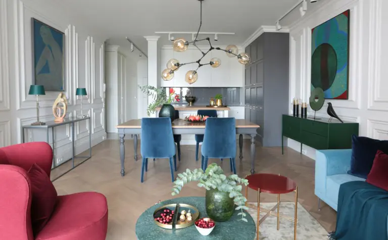 Wnętrze z zieloną komodą, niebieskimi krzesłami i roślinami - styl minimaluxe, quiet luxury.