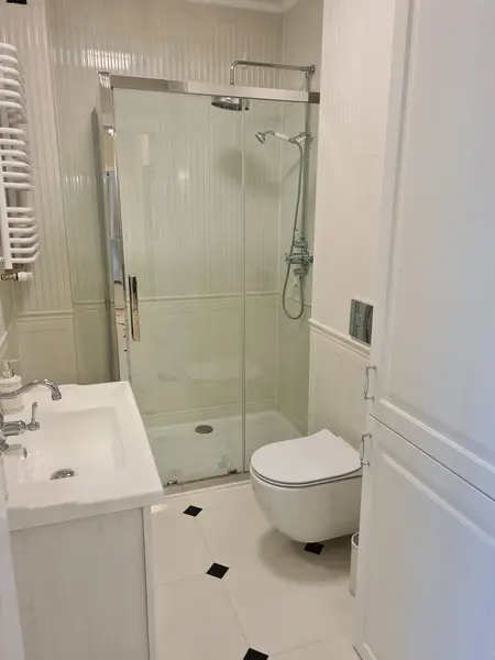 Tradycyjna łazienka z kabiną prysznicową, białymi meblami i eleganckimi akcentami.