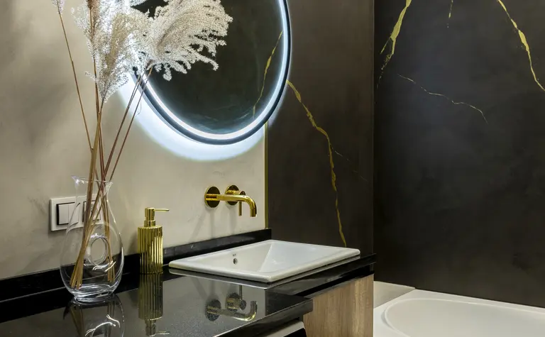 Nowoczesna łazienka z minimalistycznym designem, złotymi detalami i eleganckim oświetleniem