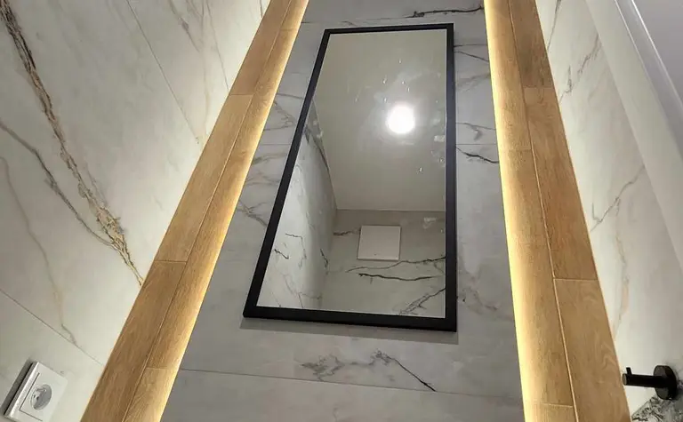 Wnętrze łazienki z marmurowymi ścianami i drewnem, minimalistyczny design.
