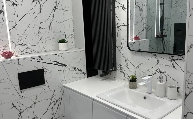 Nowoczesna łazienka z minimalistycznym designem, białe meble i czarne płytki.