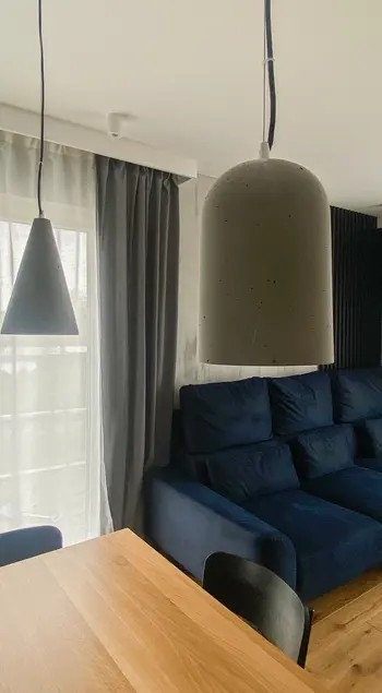 Minimalistyczne wnętrze salonu z nowoczesną sofą i lampami w stylu quiet luxury.