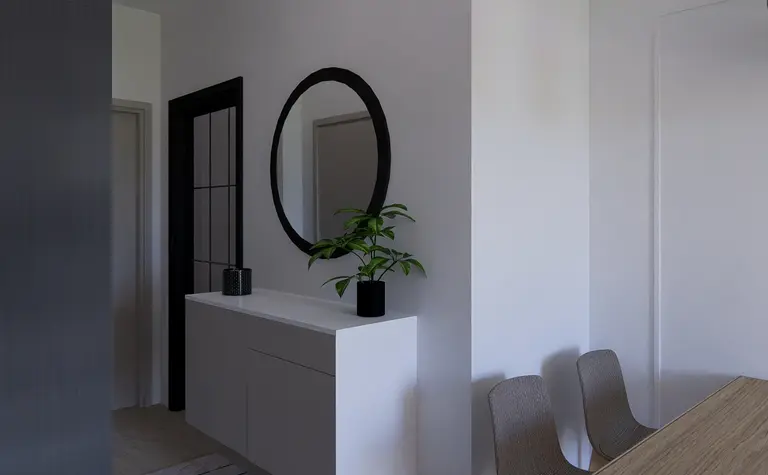 Przedpokój w stylu minimalistycznym z białą komodą i okrągłym lustrem.
