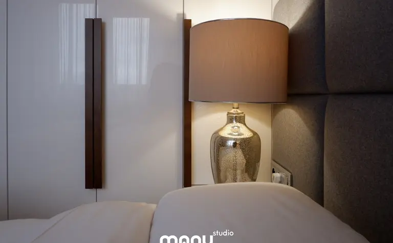Sypialnia z tradycyjnym zagłówkiem i lampą w eleganckim stylu.