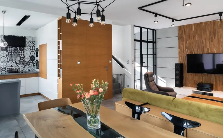 Wnętrze salonu w stylu industrialnym z minimalistycznym wystrojem, drewnianą ścianą i nowoczesnymi akcentami.