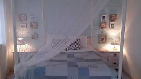 Sypialnia w stylu boho z jasnymi ścianami, łóżkiem i lampkami.