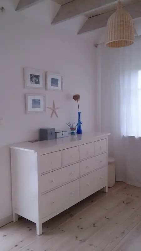 Wnętrze z białą komodą, niebieską wazą i elementami boho, rustykalnymi oraz vintage.