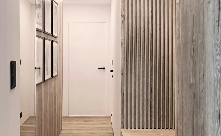 Przedpokój w stylu japandi z drewnianymi elementami i nowoczesnym oświetleniem.