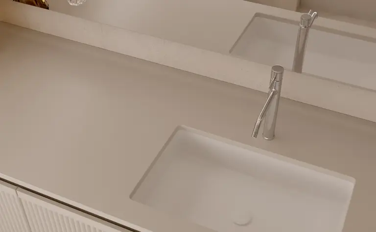 Minimalistyczna łazienka z beżowymi meblami i przezroczystymi dekoracjami.