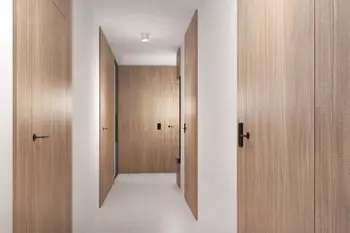 Korytarz z minimalistycznym designem, drewniane drzwi i jasne ściany